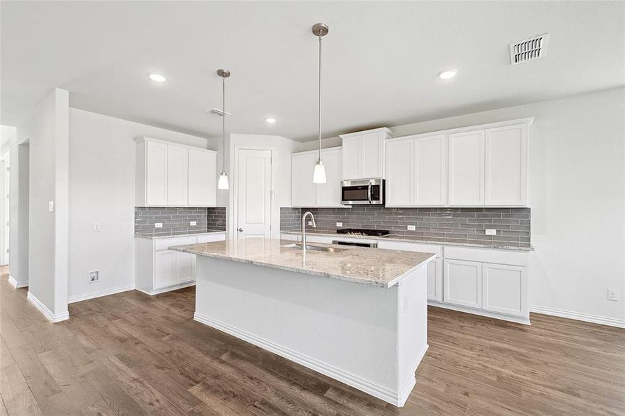 Kitchen with light hardwood / wood-style floors, white cabinets, and stainless steel appliances