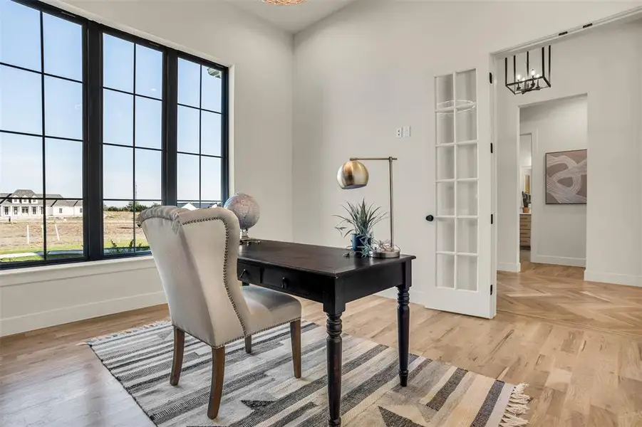 Home office with light wood-type flooring and a chandelier
