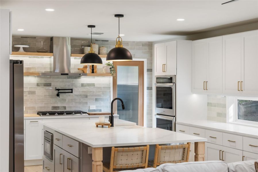Kitchen with white cabinetry, decorative backsplash, stainless steel appliances, and island range hood