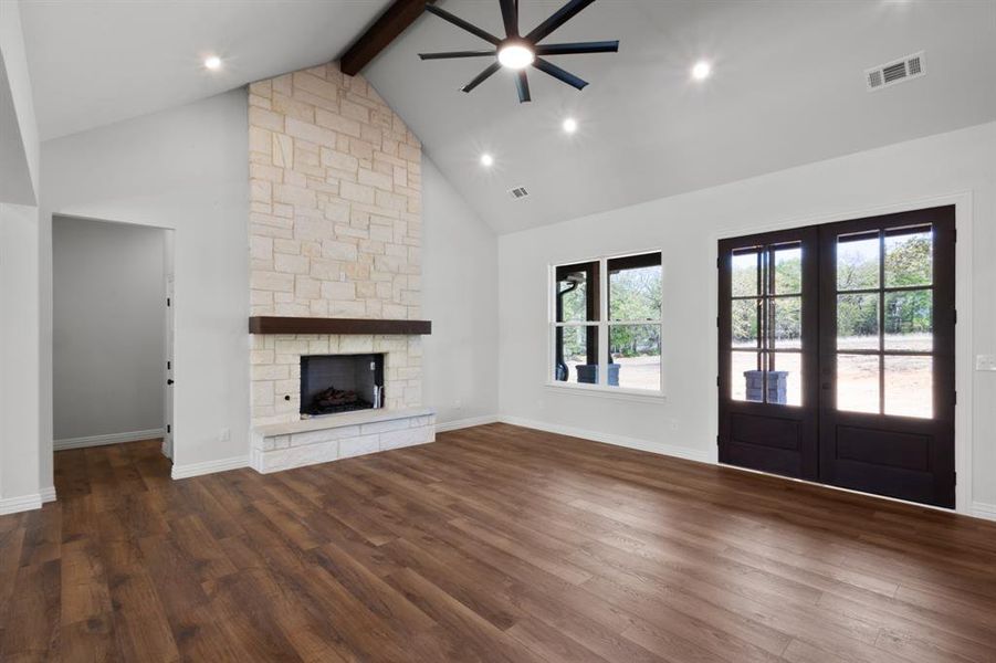 Unfurnished living room with high vaulted ceiling, plenty of natural light, beamed ceiling, and ceiling fan