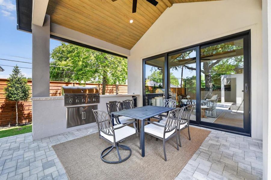 Covered patio with a high vaulted wood-finish ceiling, featuring an integrated stainless steel grill and a built-in countertop Covered patio with a high vaulted wood-finish ceiling, featuring an integrated stainless steel grill and a built-in countertop