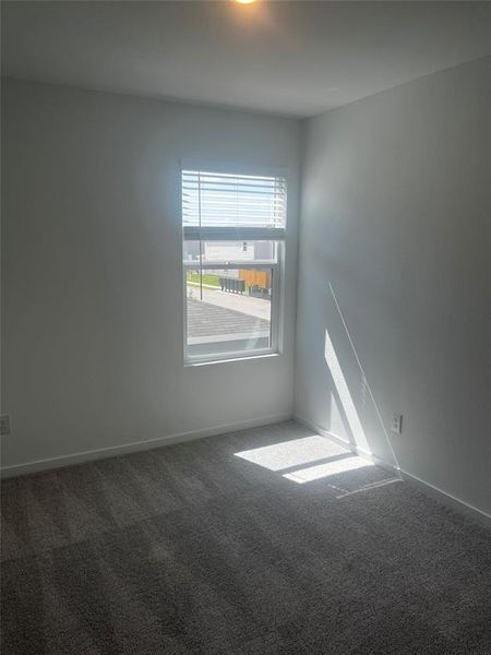 Interior room featuring a single window with horizontal blinds, neutral wall paint, and gray textured carpeting Interior room featuring a single window with horizontal blinds, neutral wall paint, and gray textured carpeting