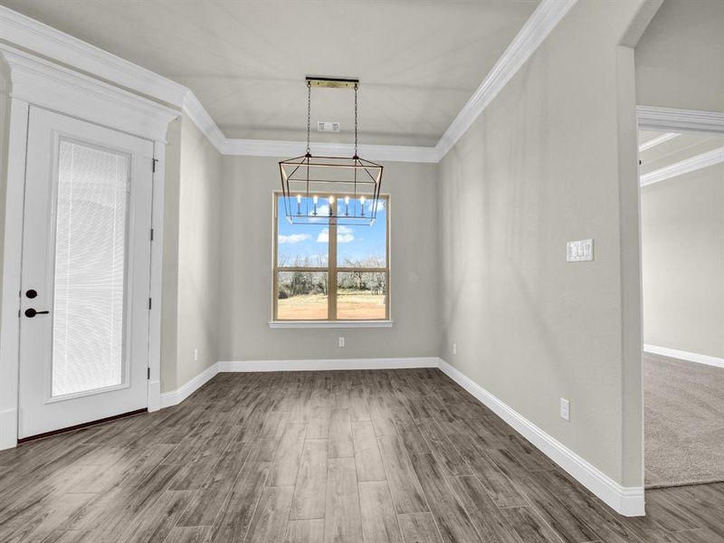 Unfurnished dining area with crown molding, wood-type flooring, and an inviting chandelier