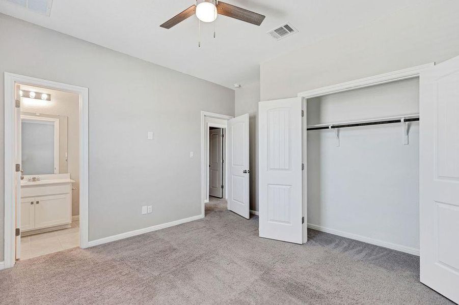 Unfurnished bedroom with light colored carpet, a closet, a ceiling fan, and ensuite bathroom Unfurnished bedroom with light colored carpet, a closet, a ceiling fan, and ensuite bathroom