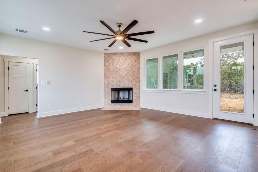 Unfurnished living room with a tile fireplace, ceiling fan, light wood-style floors, and recessed lighting