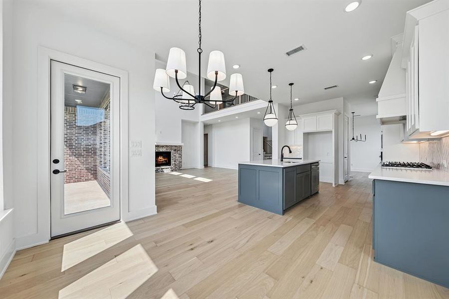 Kitchen featuring a chandelier, a kitchen island with sink, white cabinetry, hanging light fixtures, and open floor plan