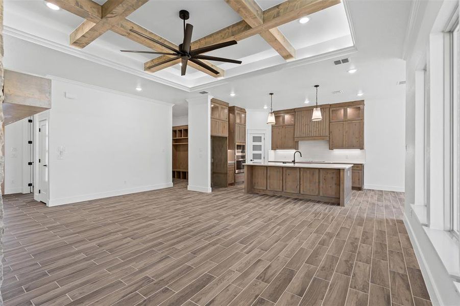 Kitchen featuring coffered ceiling, recessed lighting, beam ceiling, open floor plan, and light countertops Kitchen featuring coffered ceiling, recessed lighting, beam ceiling, open floor plan, and light countertops