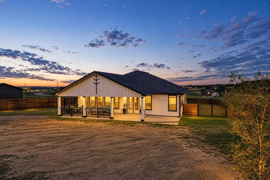 An inviting covered back porch provides comfortable outdoor living space against a dramatic sunset sky. An inviting covered back porch provides comfortable outdoor living space against a dramatic sunset sky.