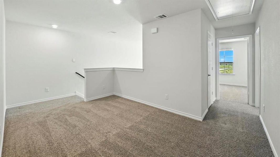 Carpeted empty room with attic access and baseboards