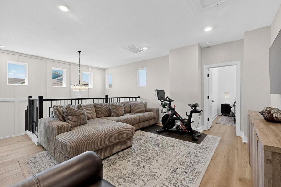Bonus Living room on Upper level, light wood finished floors, a chandelier, and attic access