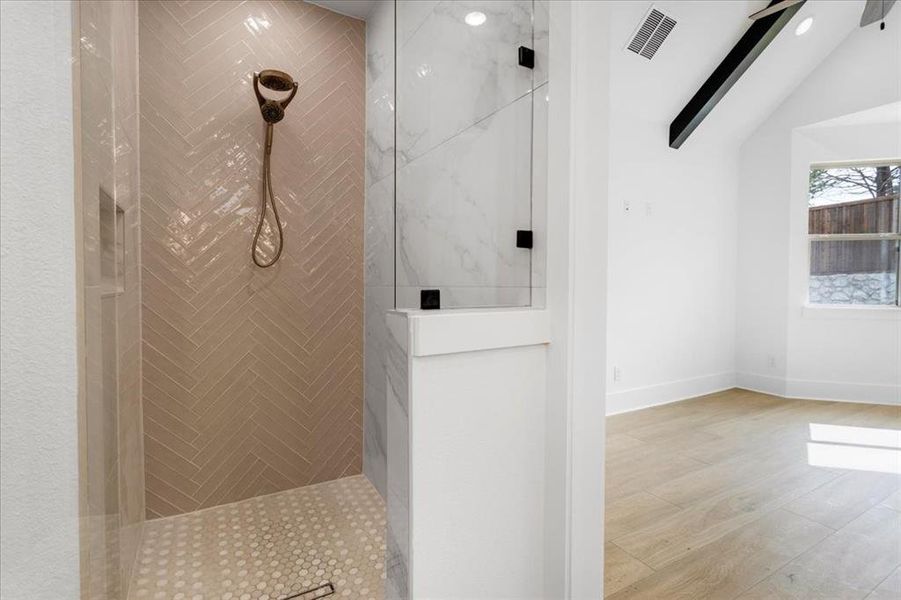 Bathroom featuring a marble finish shower and light wood finished floors