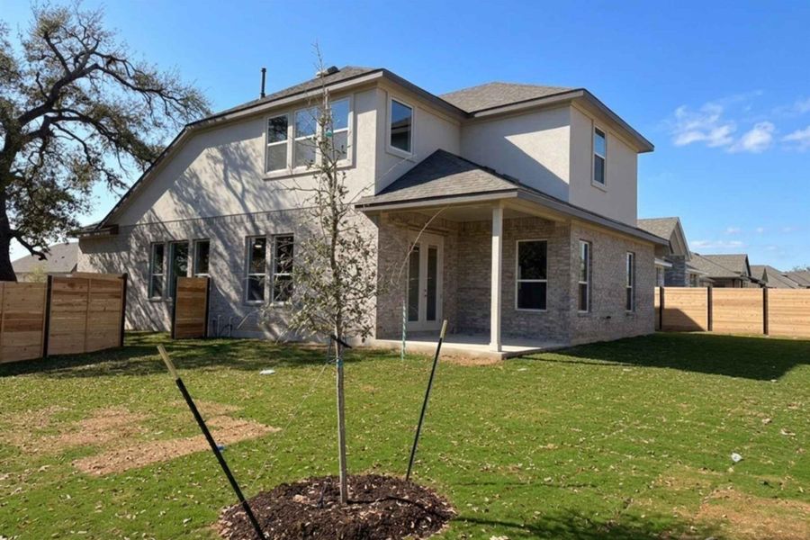 Rear view of property with a patio, brick siding, a fenced backyard, and stucco siding