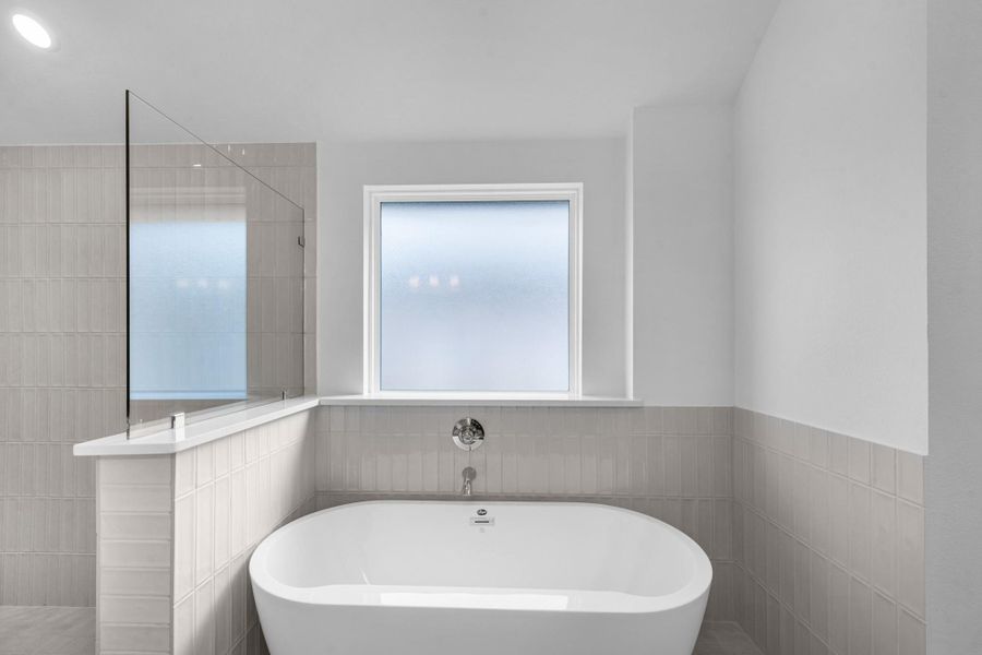 Additional view of the standing tub, shower, and floor to ceiling tile accents with beautiful neutral tones. Additional view of the standing tub, shower, and floor to ceiling tile accents with beautiful neutral tones.