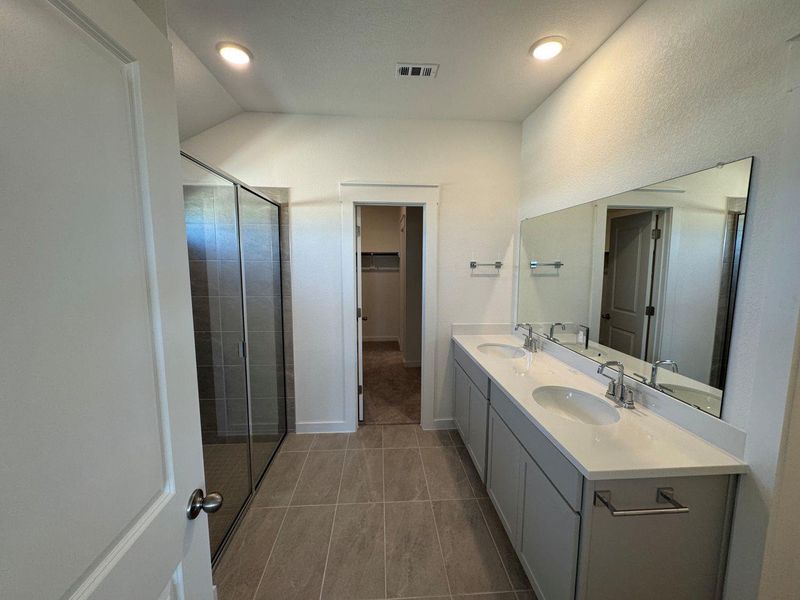 Full bath featuring a walk in closet, double vanity, a shower stall, light tile patterned floors, and recessed lighting Full bath featuring a walk in closet, double vanity, a shower stall, light tile patterned floors, and recessed lighting
