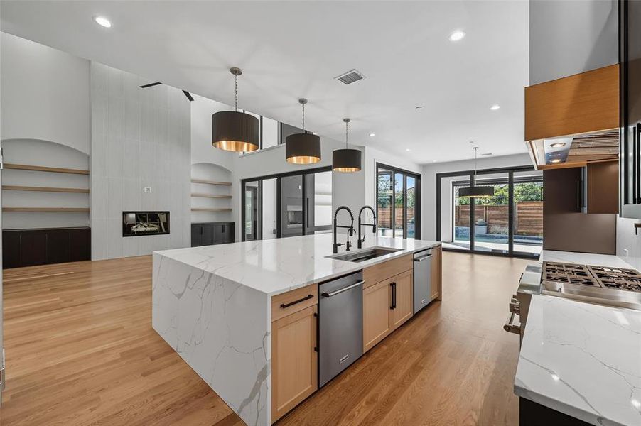 Example Open-concept living space with a large kitchen island featuring a waterfall-edge countertop and integrated sink Example Open-concept living space with a large kitchen island featuring a waterfall-edge countertop and integrated sink