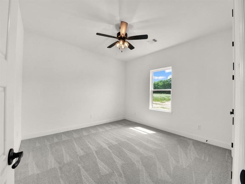 Carpeted empty room with ceiling fan and baseboards