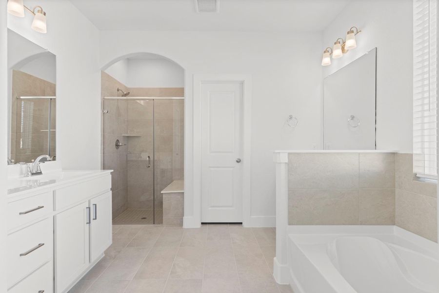 The spa-inspired primary bath offers dual sinks, a spacious vanity, and a beautifully tiled walk-in shower. Bright, fresh, and designed for everyday comfort.  Gorgeous large tile floors.  Look at that seamless glass shower with the mud bottom, no cheap plastic bottom in this home shower!