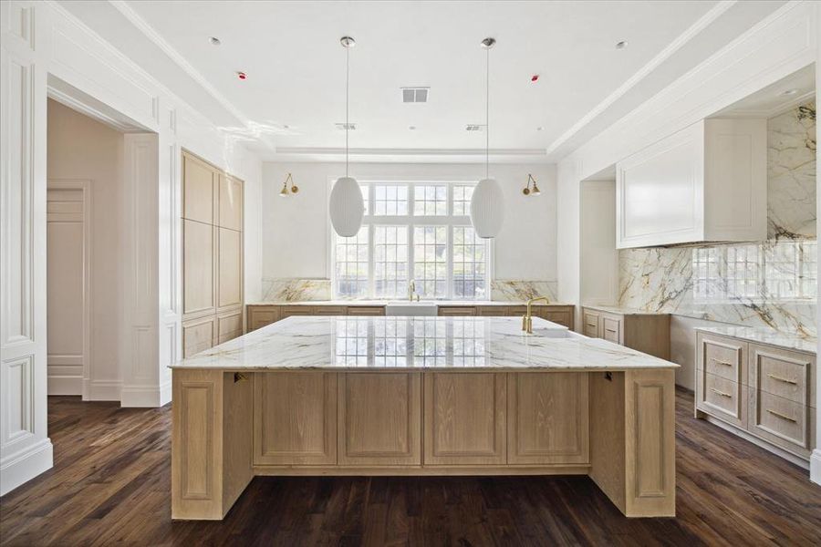 The kitchen features handsome wood floors, a spacious working island with an under-mount sink, and sleek pendant light fixtures above the island. This kitchen is a chef's dream!