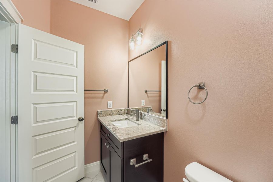 Half bathroom featuring vanity and light tile patterned flooring