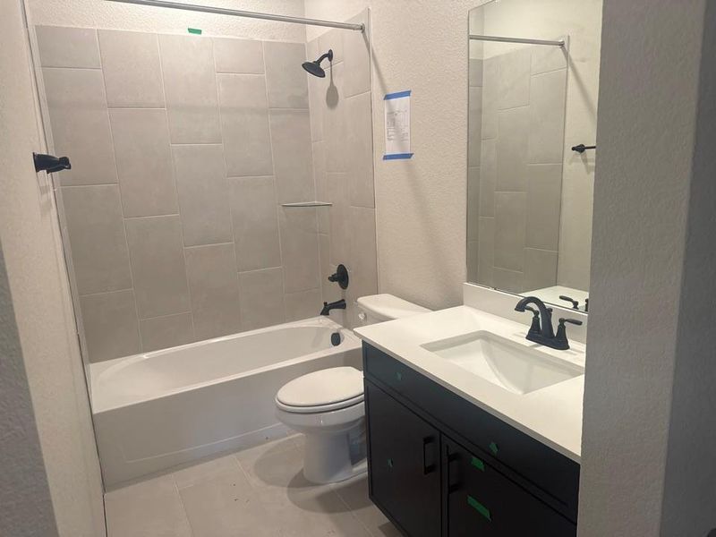 Bathroom featuring a textured wall, washtub / shower combination, vanity, and light tile patterned flooring Bathroom featuring a textured wall, washtub / shower combination, vanity, and light tile patterned flooring