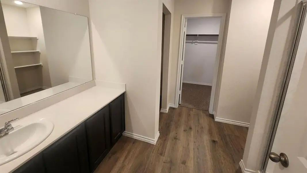 Bathroom vanity with a white oval sink, chrome faucet, and expansive wall-mounted mirror