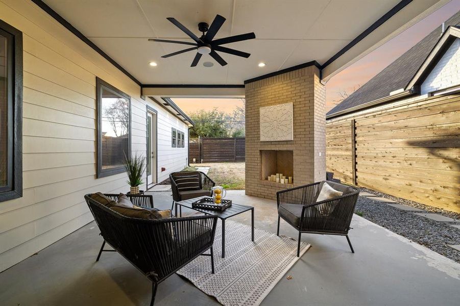 Patio terrace at dusk with ceiling fan and an outdoor living space with a fireplace