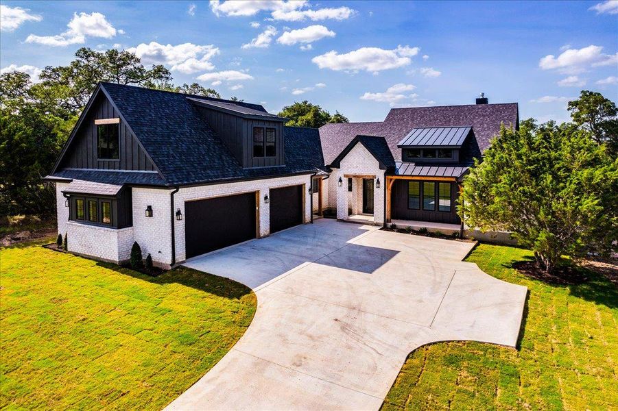 A striking modern farmhouse with clean lines, a dramatic dark roof, and inviting curb appeal.