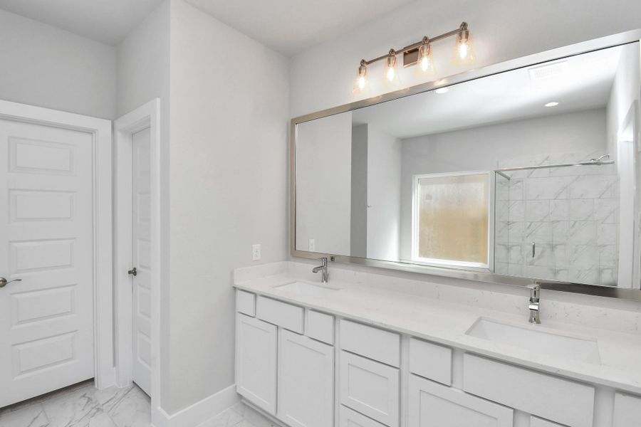 Escape to a spa-like oasis in this primary bathroom. Enjoy a walk-in shower with tile surround, a separate garden tub with custom detailing, and an elegant vanity featuring light countertops, modern hardware, and beautiful vanity lights. Experience luxury and relaxation in every detail. Sample photo of completed home with similar floor plan. Actual colors and selections may vary. Escape to a spa-like oasis in this primary bathroom. Enjoy a walk-in shower with tile surround, a separate garden tub with custom detailing, and an elegant vanity featuring light countertops, modern hardware, and beautiful vanity lights. Experience luxury and relaxation in every detail. Sample photo of completed home with similar floor plan. Actual colors and selections may vary.