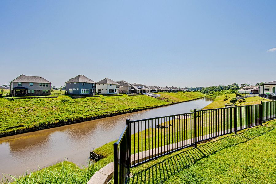 Daytime view of the fenced backyard and scenic neighborhood waterway