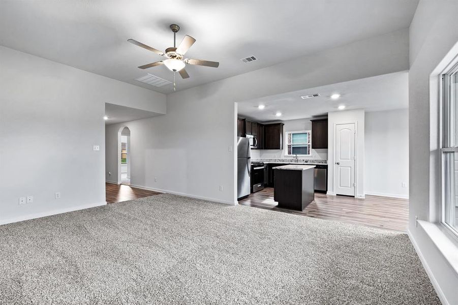 Unfurnished living room featuring sink, carpet, and ceiling fan