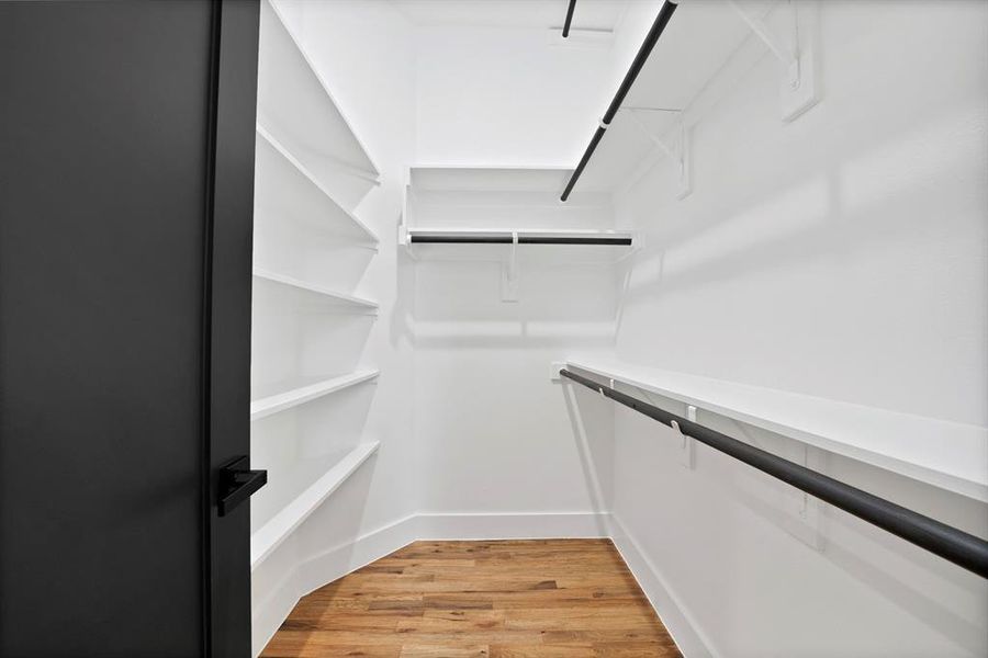 Walk-in closet featuring built-in shelving, hanging rods, and wood-look flooring