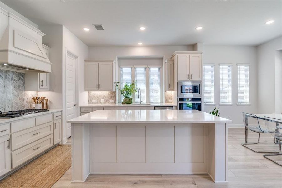 Kitchen with a center island, a sink, light countertops, appliances with stainless steel finishes, and visible vents Kitchen with a center island, a sink, light countertops, appliances with stainless steel finishes, and visible vents