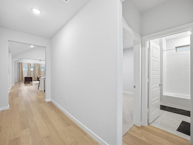 Hall featuring light wood finished floors, recessed lighting, and lofted ceiling