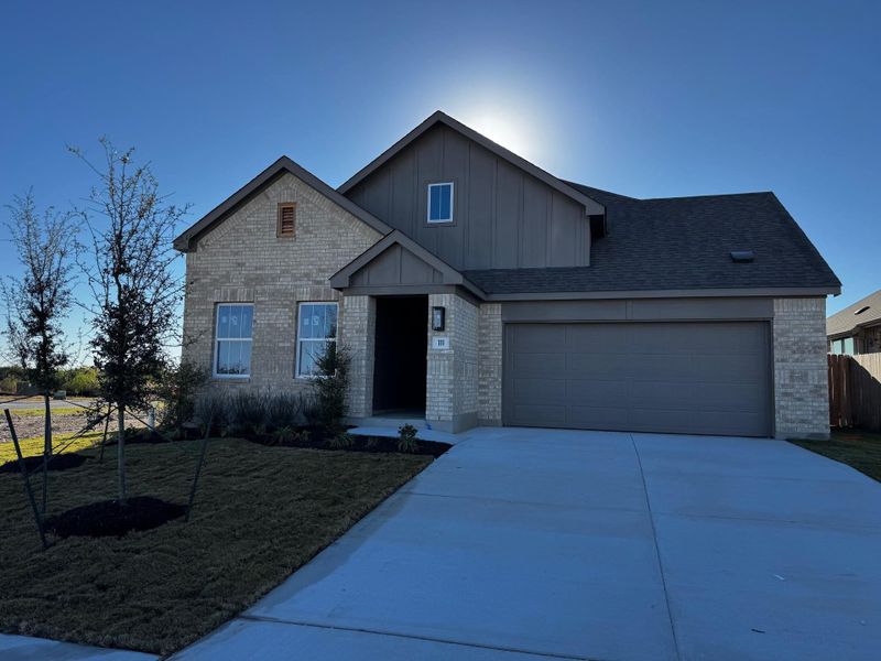 View of front facade with board and batten siding, brick siding, driveway, a front yard, and a garage View of front facade with board and batten siding, brick siding, driveway, a front yard, and a garage