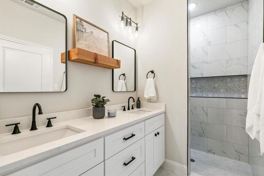 Bathroom vanity featuring dual under-mount sinks, white cabinetry with black hardware, and black-finish faucets