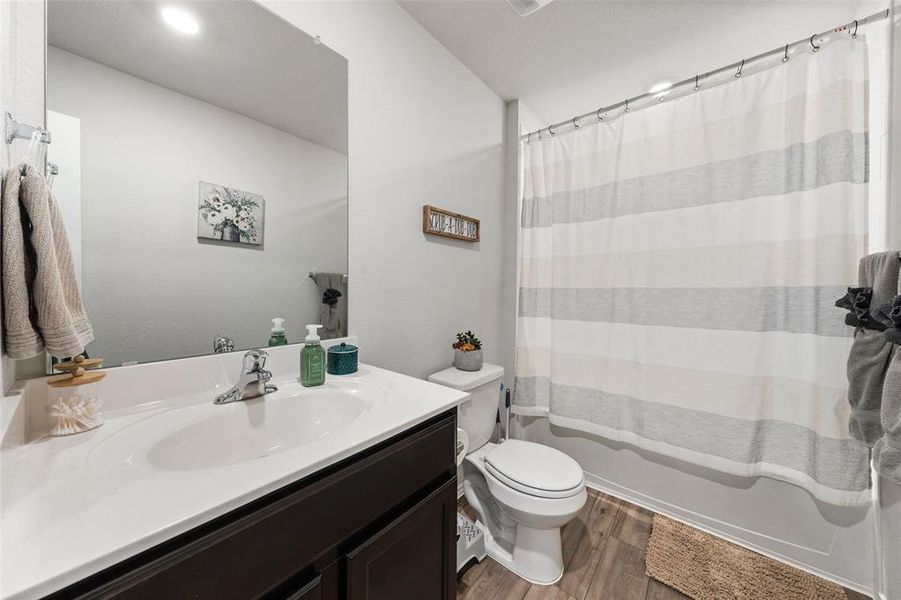 Bathroom with vanity, dark wood-style floors, and shower / bath combination with curtain