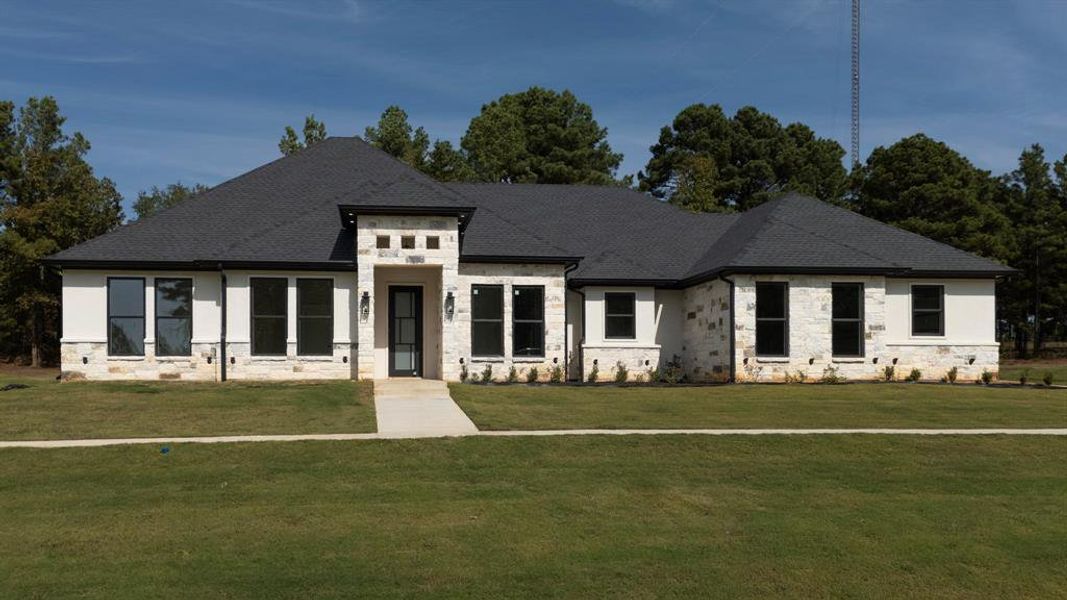 View of front of home with stone siding, a front lawn, and roof with shingles View of front of home with stone siding, a front lawn, and roof with shingles