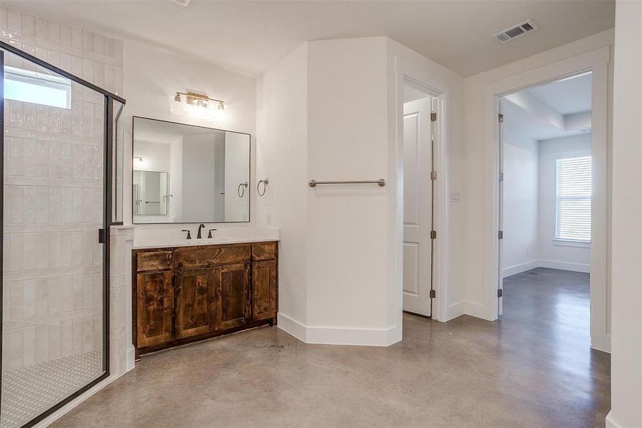 Bathroom featuring vanity, a healthy amount of sunlight, walk in shower, and concrete floors
