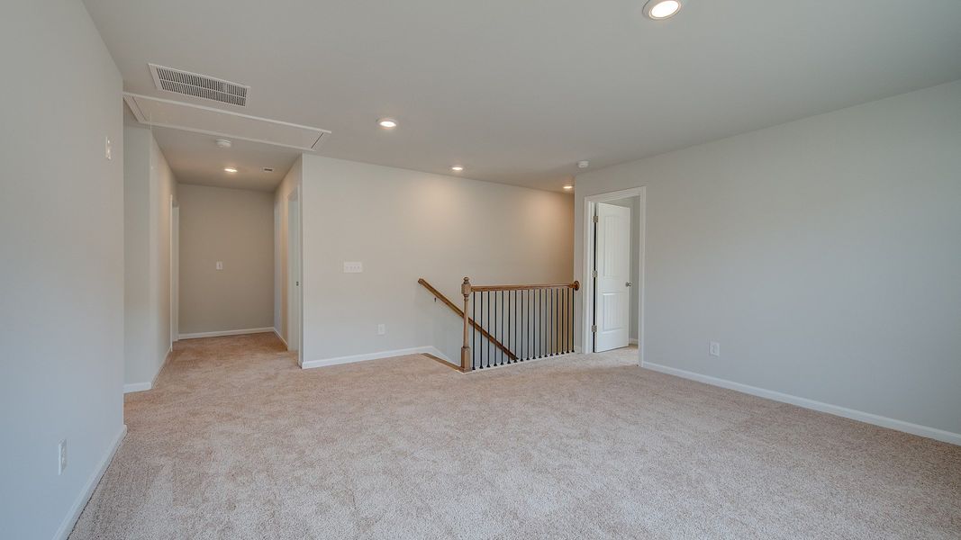 Spacious Ridgewood loft for work or lounge use with carpet flooring and natural light at Bowers Farm in McDonough, GA.