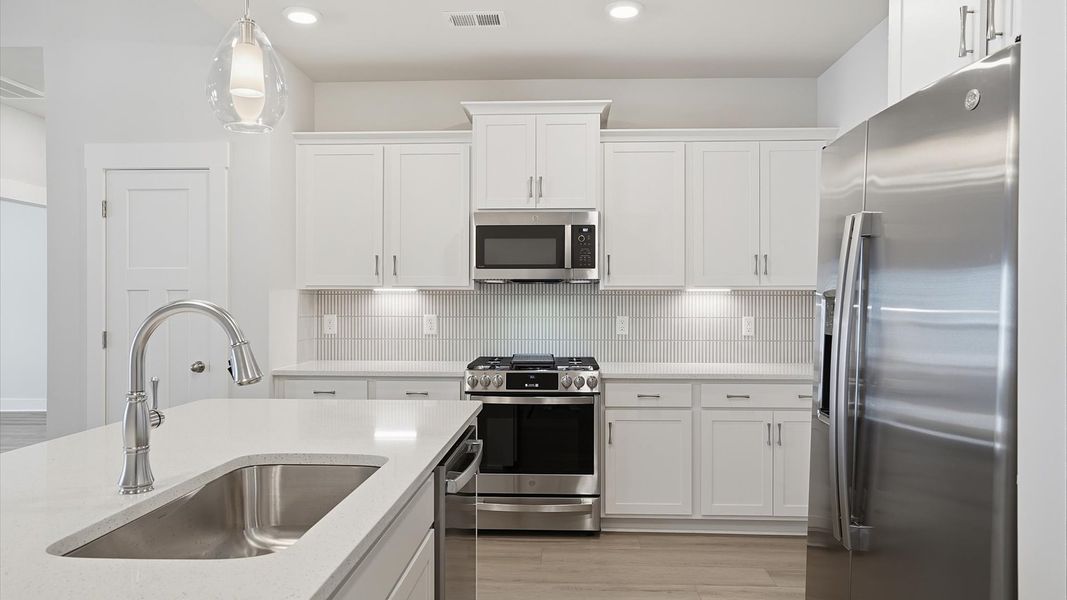 Superior craftsmanship shines in this modern kitchen with a space-saving island and open flow at Village at Midway
