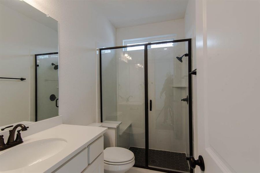 Bathroom featuring vanity, toilet, and an enclosed shower