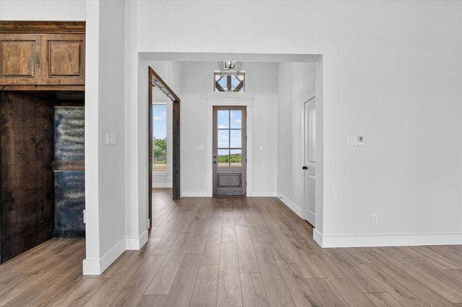 Foyer with light wood-style flooring and hanging lights