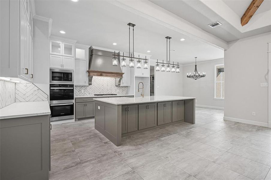 Kitchen featuring decorative backsplash, a large island with sink, hanging light fixtures, light stone countertops, and recessed lighting Kitchen featuring decorative backsplash, a large island with sink, hanging light fixtures, light stone countertops, and recessed lighting