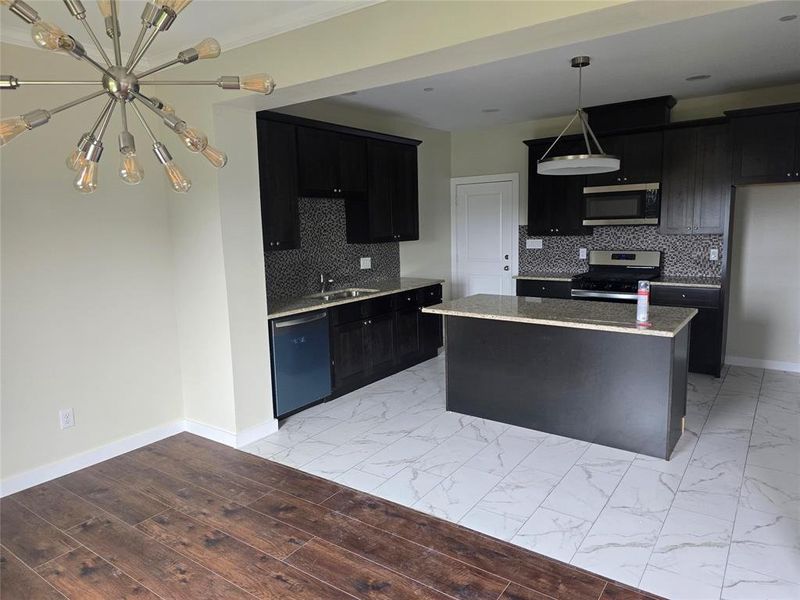 Kitchen featuring stainless steel appliances, dark cabinetry, and baseboards