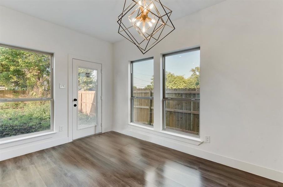 Unfurnished dining area with hardwood / wood-style flooring, a wealth of natural light, and a chandelier