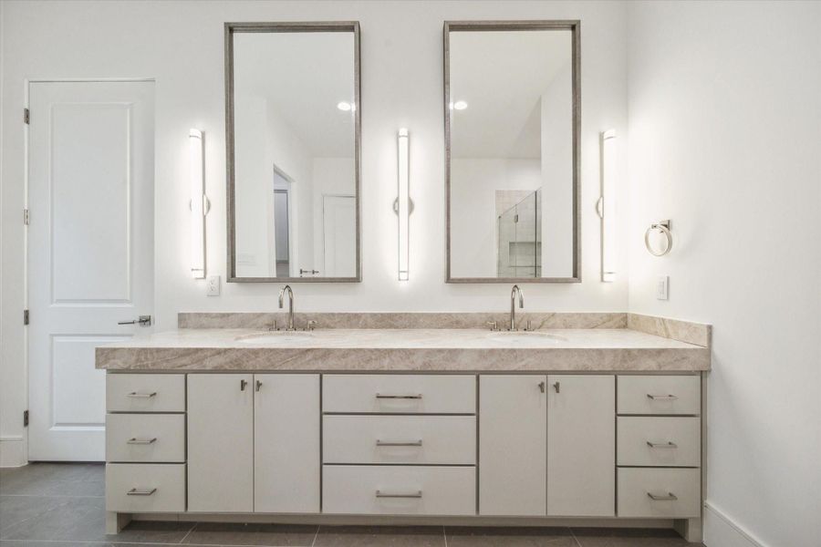 Custom Benedettini cabinetry, Leathered Taj Mahal Quartzite countertops, Kallista Perfect under-mount oval sinks with Kallista One fixtures, and sconces with polished nickel detail complete this luxurious bathroom. Custom Benedettini cabinetry, Leathered Taj Mahal Quartzite countertops, Kallista Perfect under-mount oval sinks with Kallista One fixtures, and sconces with polished nickel detail complete this luxurious bathroom.