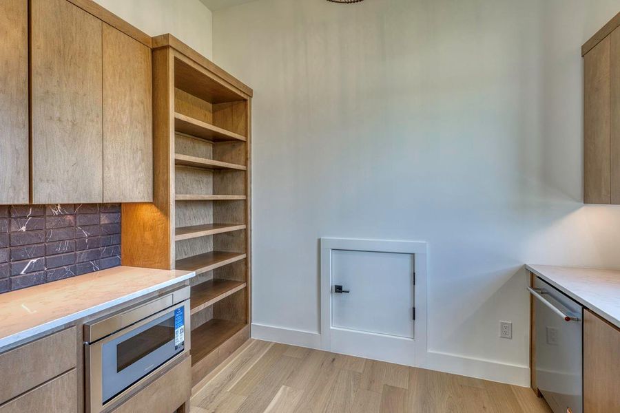 Ample custom cabinetry and warm wood flooring define this functional service pantry.