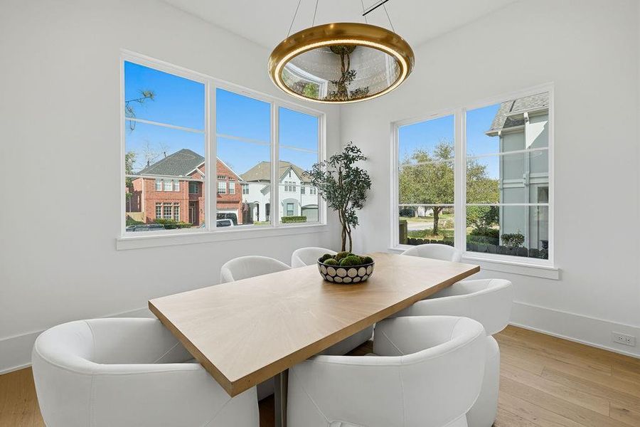 The formal dining room is designed to transition effortlessly from bright, sun-filled brunches to sophisticated evening gatherings. The space is anchored by a high-end gold-finished halo pendant featuring a textured glass inlay that creates a soft, diffused glow, perfectly complementing the natural light from the surrounding panoramic windows.
