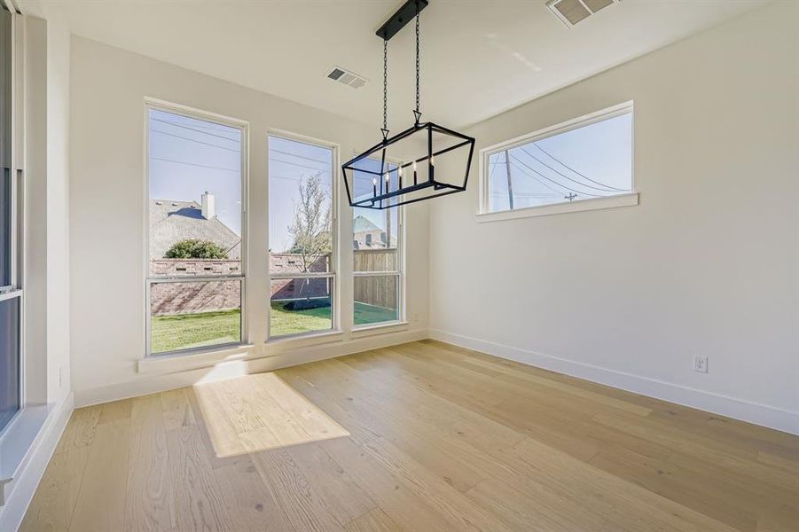 Unfurnished dining area with light wood-type flooring and a chandelier Unfurnished dining area with light wood-type flooring and a chandelier