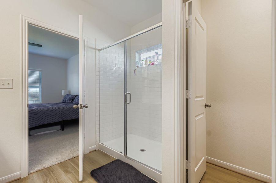 Ensuite bathroom featuring light wood-style flooring and a shower stall
